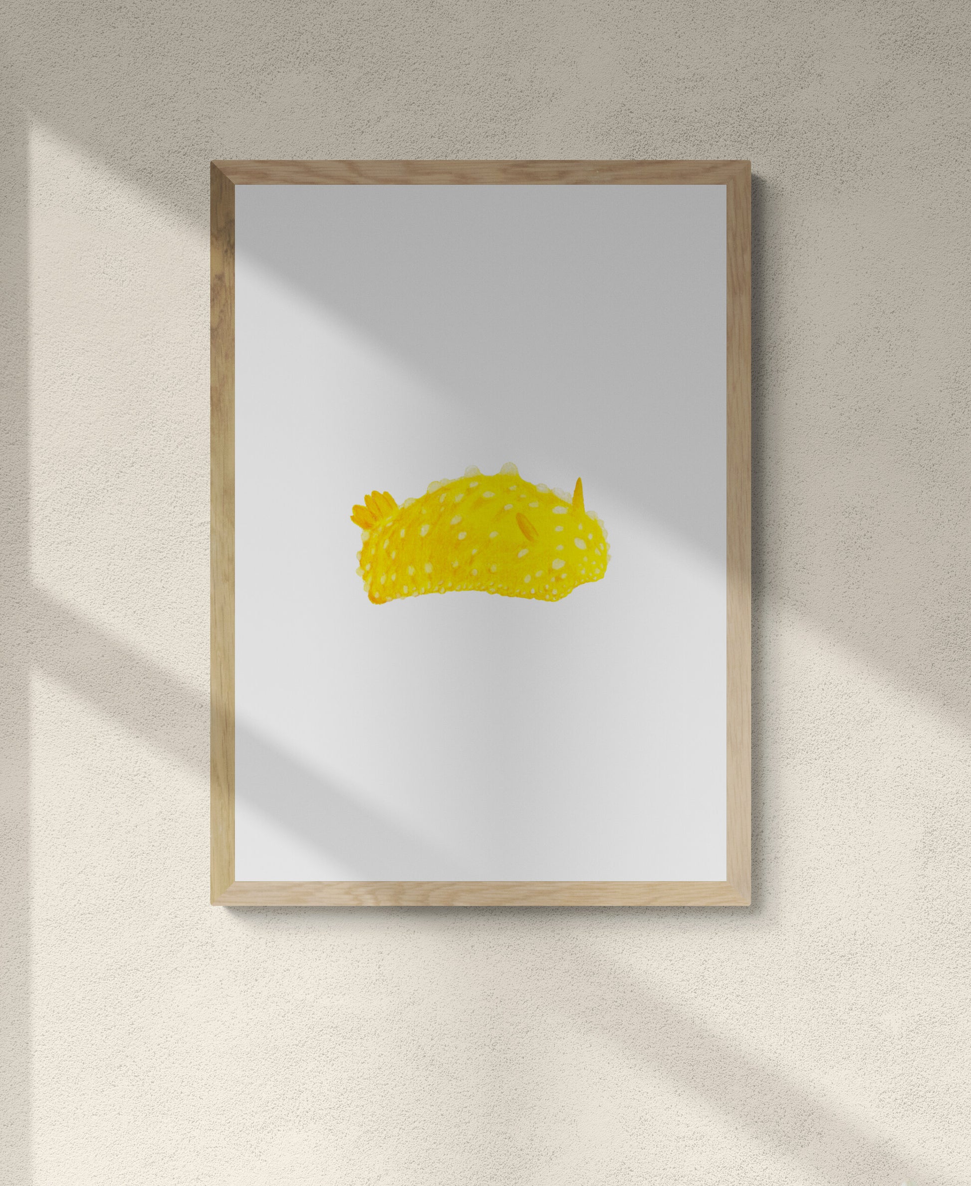 A framed art piece of a bright yellow lumpy slug type creature on a white background 