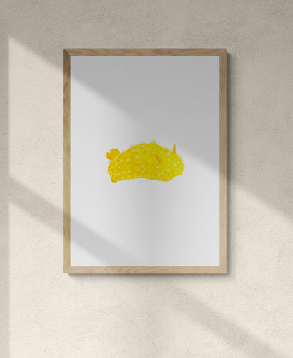 A framed art piece of a bright yellow lumpy slug type creature on a white background 